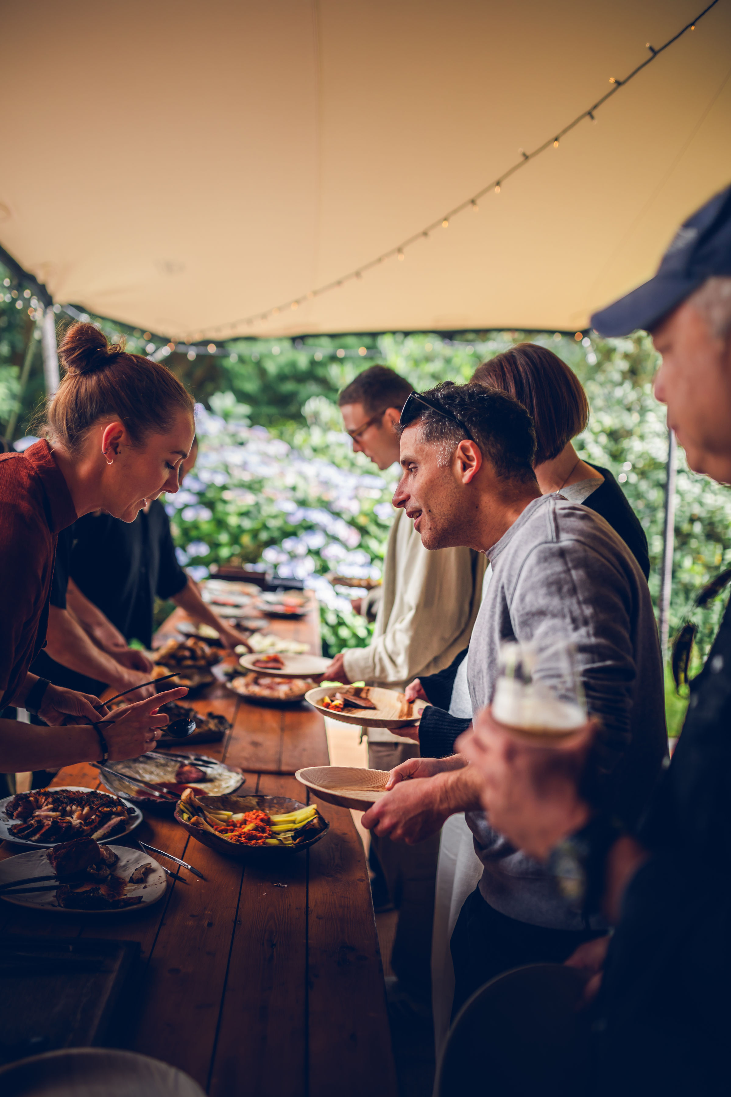 Members of the Supercar Driver Club enjoying a social gathering outdoors, sharing food and drinks, connecting with fellow supercar drivers.